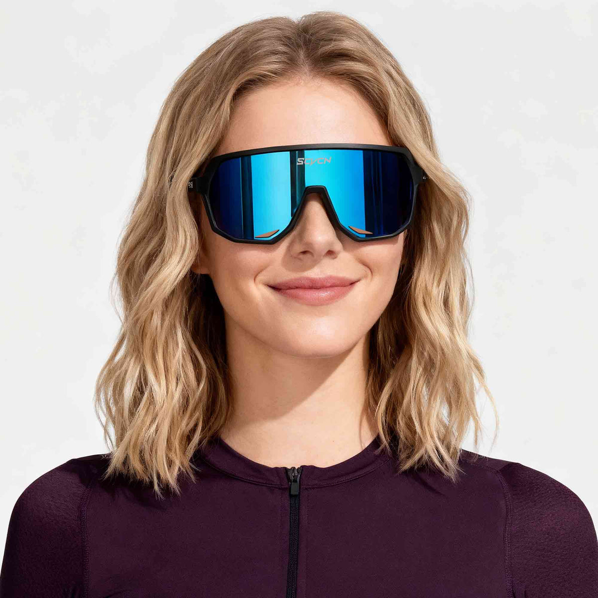Model wearing SCVCN cycling sunglasses with a blue mirrored shield lens and black frame